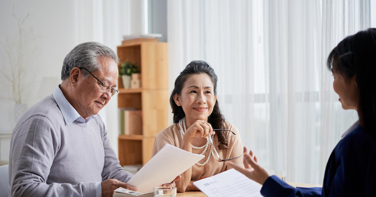 Elderly couple receiving advice and reviewing documents from a HR transformation consultant