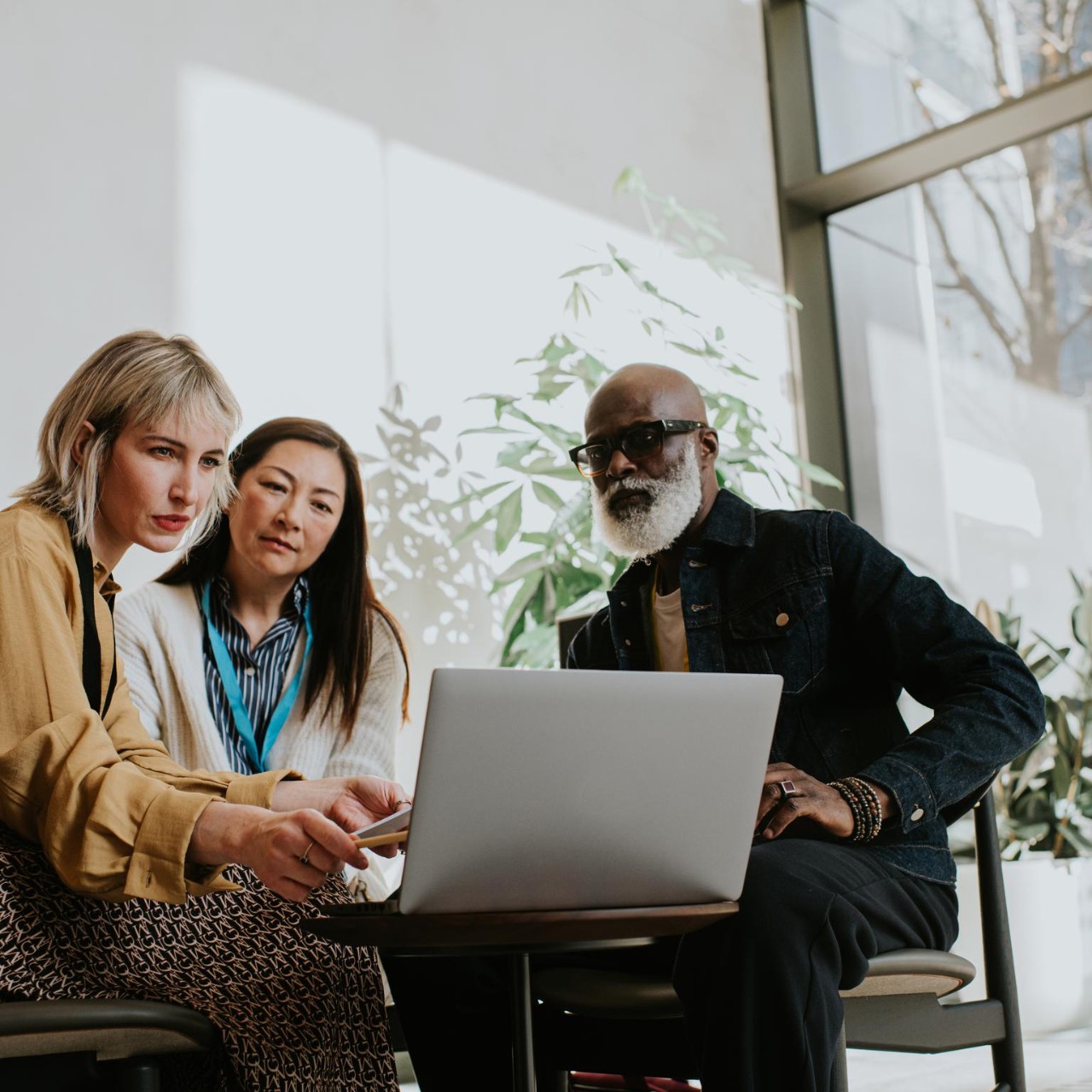 two woman and a man - sit around a laptop