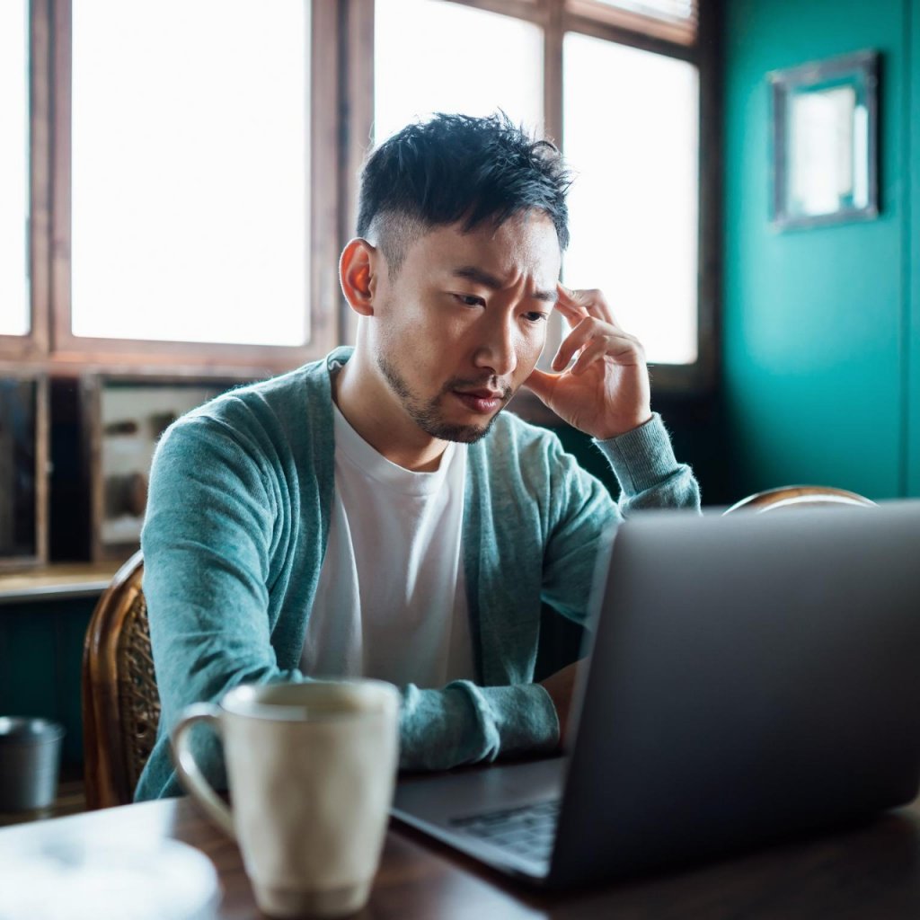 man in front of laptop looking worried