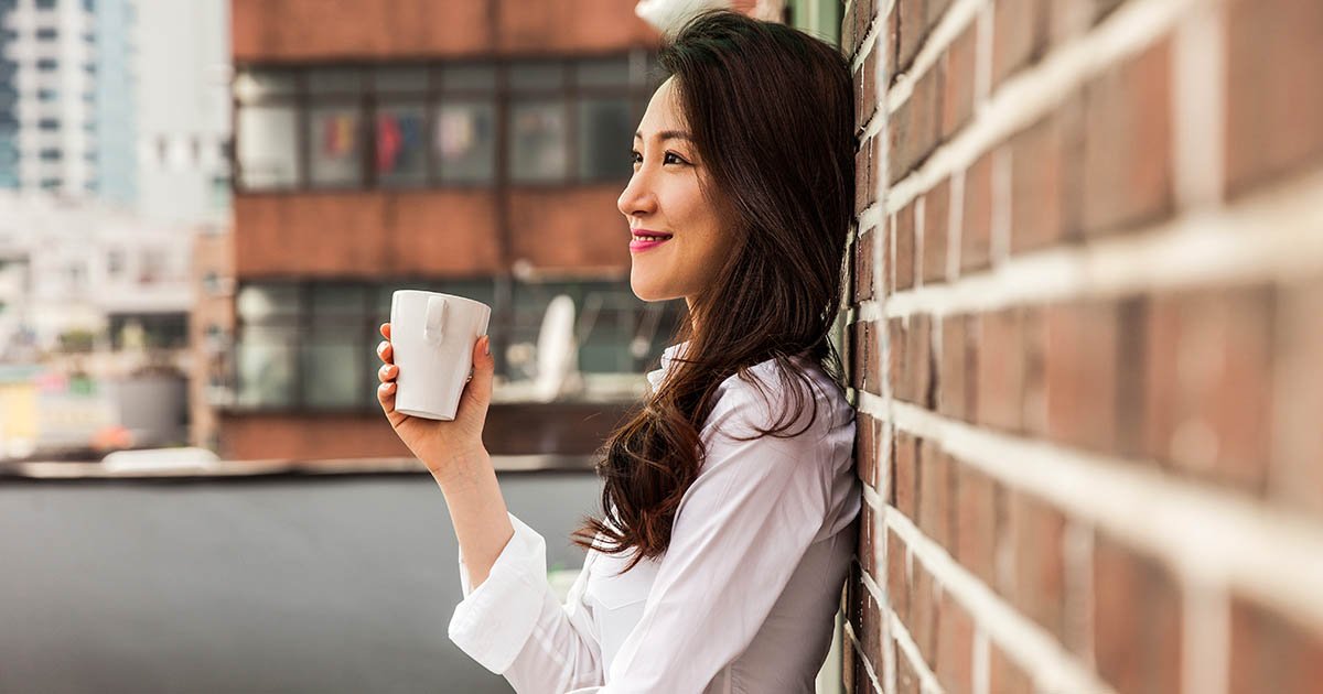 Young business woman having a break drinking an hot coffee on the rooftop of his office building in downtown Seoul, South Korea.
