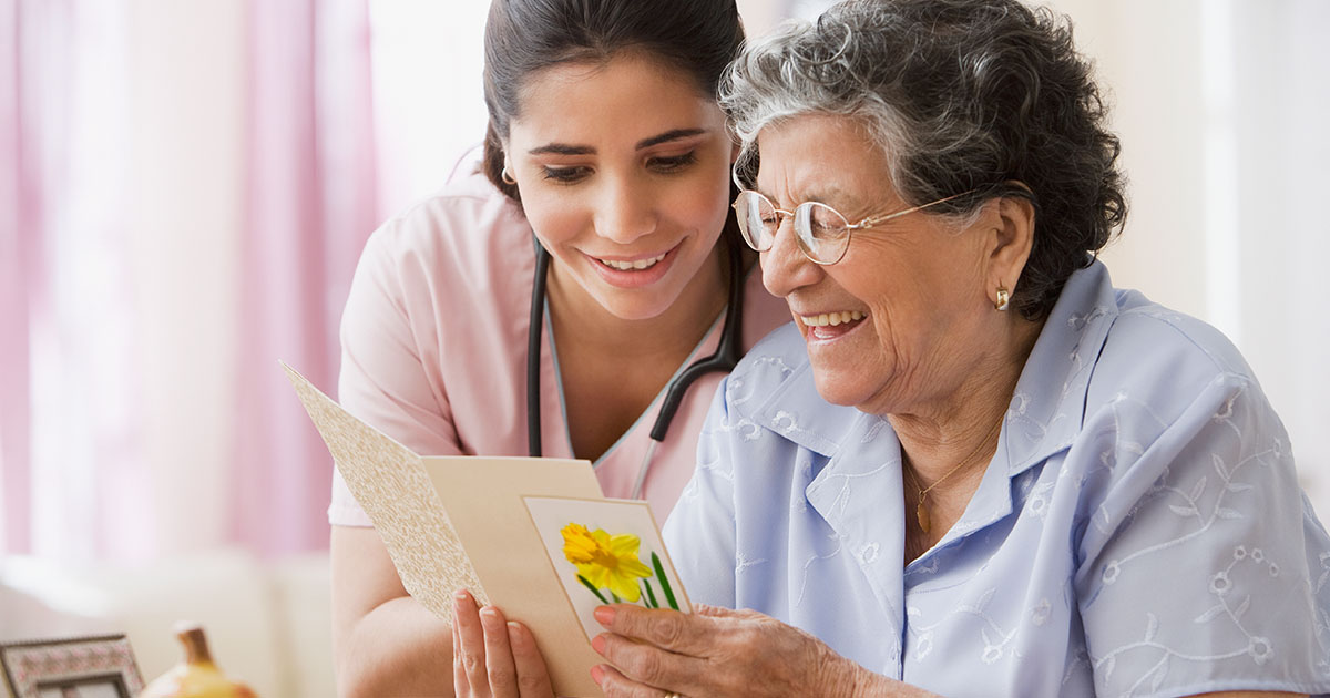 Senior Hispanic woman and nurse looking at greeting card, nursing, healthcare   25-30 years;80 plus years;aging;at home;attention;birthday;birthday card;card;caring;caucasian;celebration;color image;domestic life;enjoying;eyeglasses;front view;greeting;guidance;happy;head and shoulders;healthcare;helping;hispanic ethnicity;holding;horizontal;indoors;latin american and hispanic ethnicity;laughing;lifestyle;medical;medicine;mouth open;multi-ethnic group;nurse;nursing home;occupation;only women;people;photography;pleasure;reading;retirement;senior adult;sharing;sitting;smiling;two people;woman;young adult;25-30 years,80 plus years,aging,at home,attention,birthday,birth 