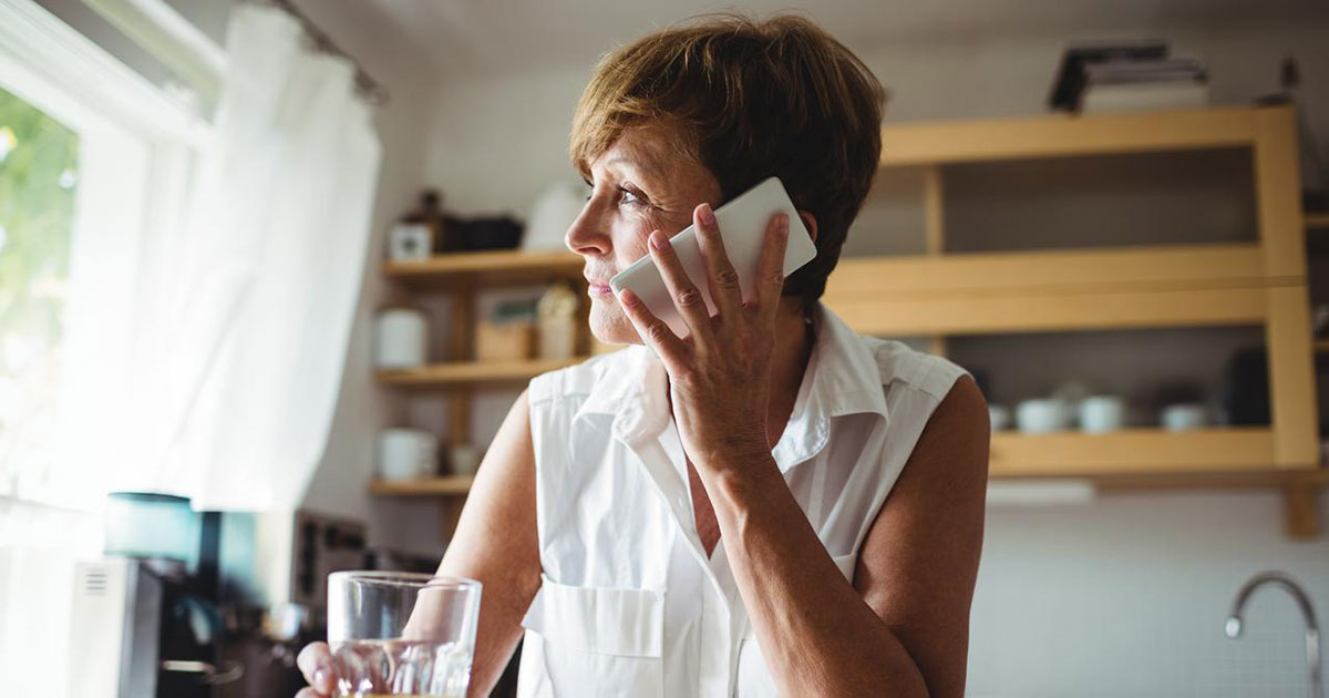 Senior woman talking on phone while having breakfast