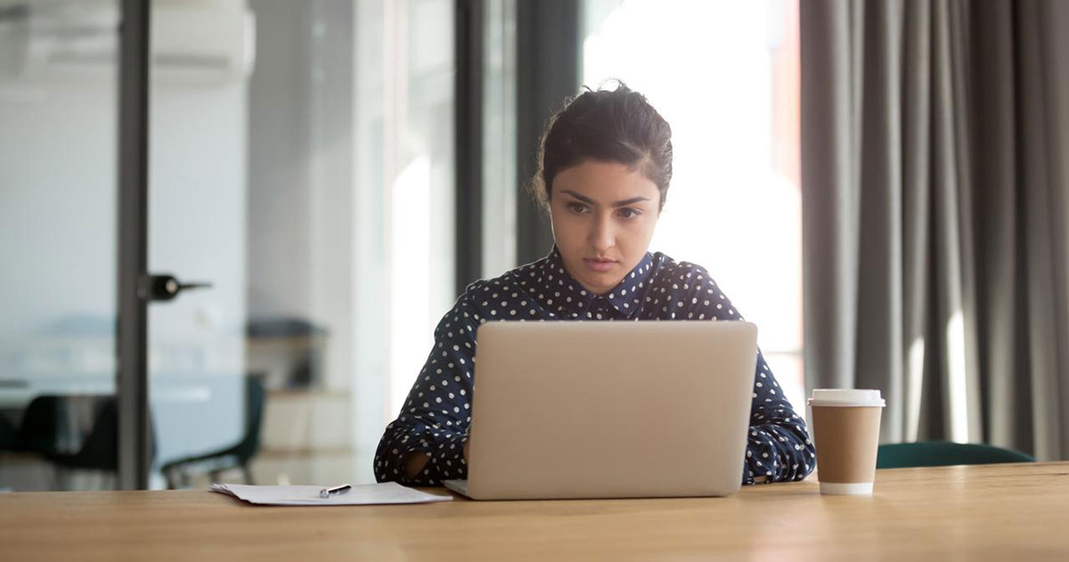 Serious indian employee working on computer at office