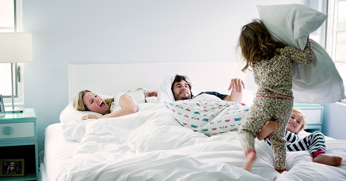 85008840 Girl playing on bed with family