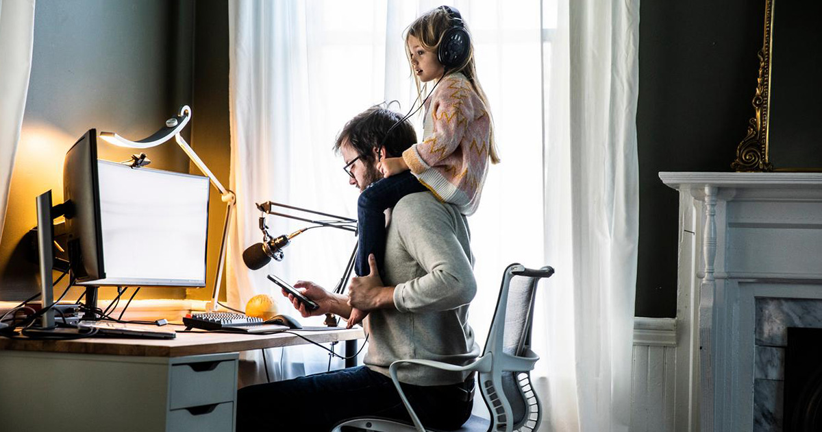 Image of a father working in home office with daughter on shoulders