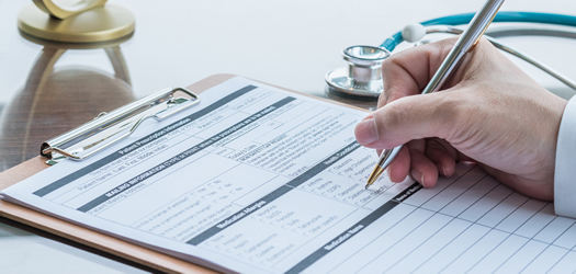 Doctor writing on medical health care record, patients discharge, or prescription form paperwork in hospital clinic