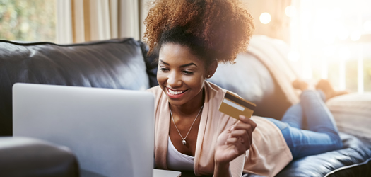 Sho of an attractive young woman shopping online while chilling at home on the sofa