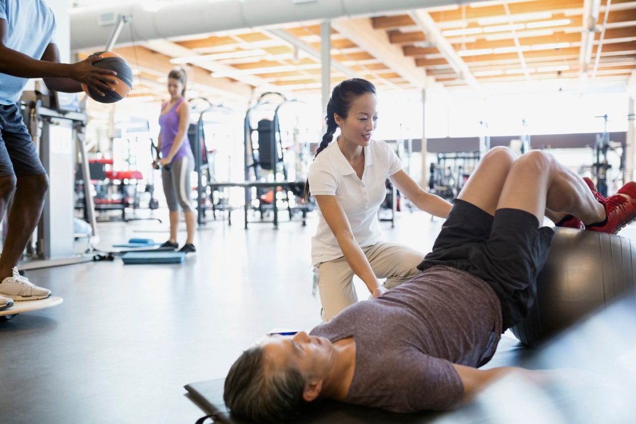 Physical therapist guiding patient fitness ball bridge pose