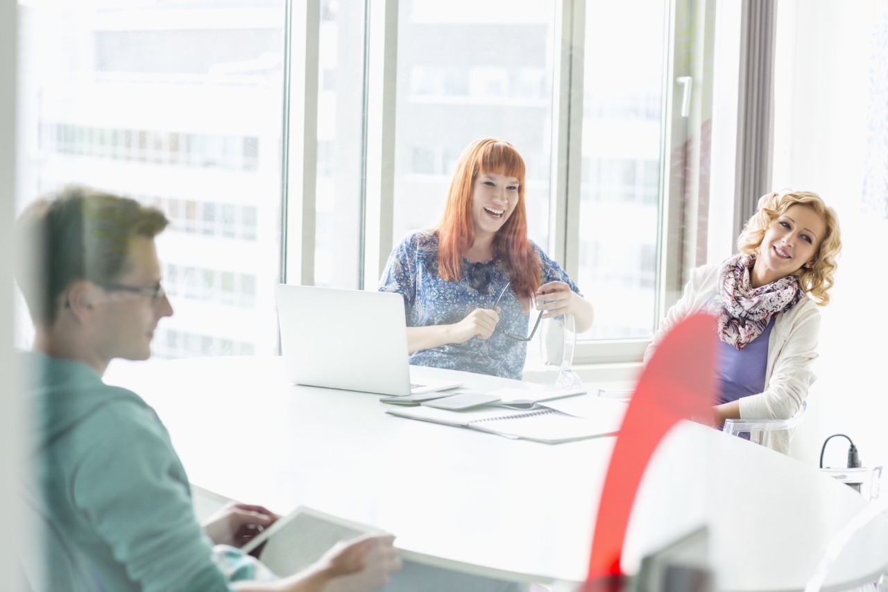 Happy businesspeople sitting at desk in creative office, group, meeting