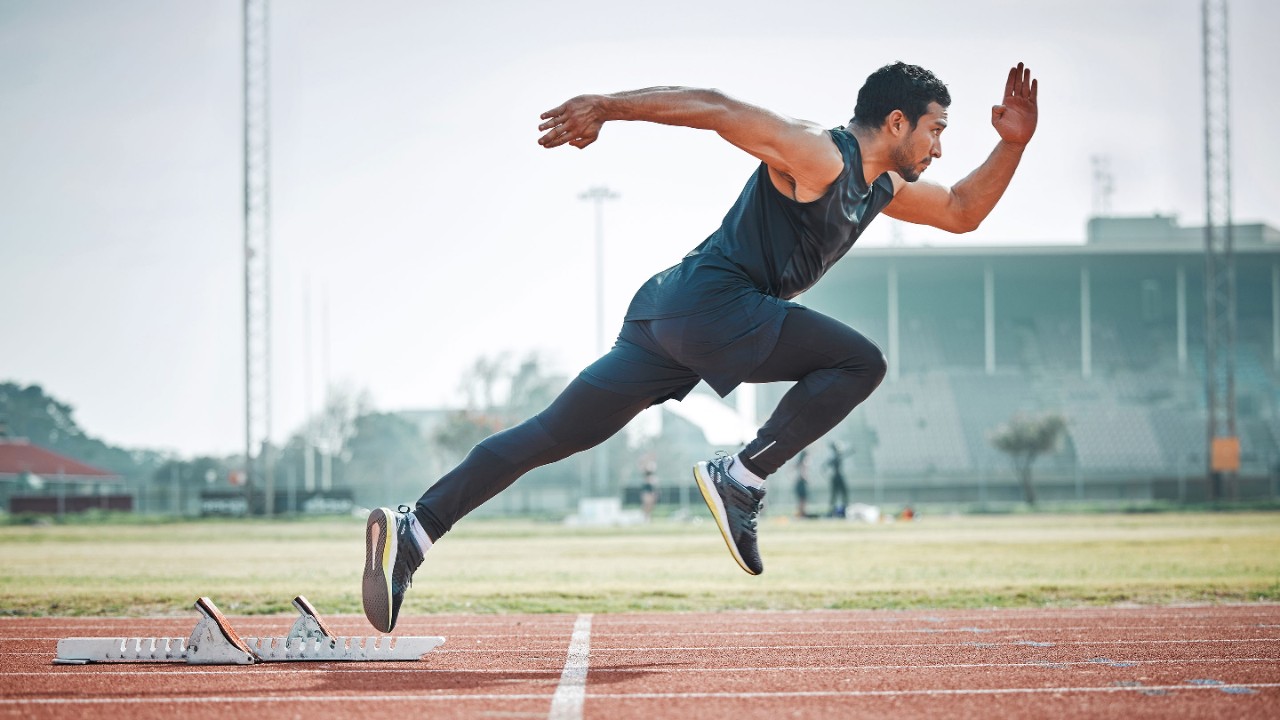 Athletic man running on arena track, sprint race training run and sports