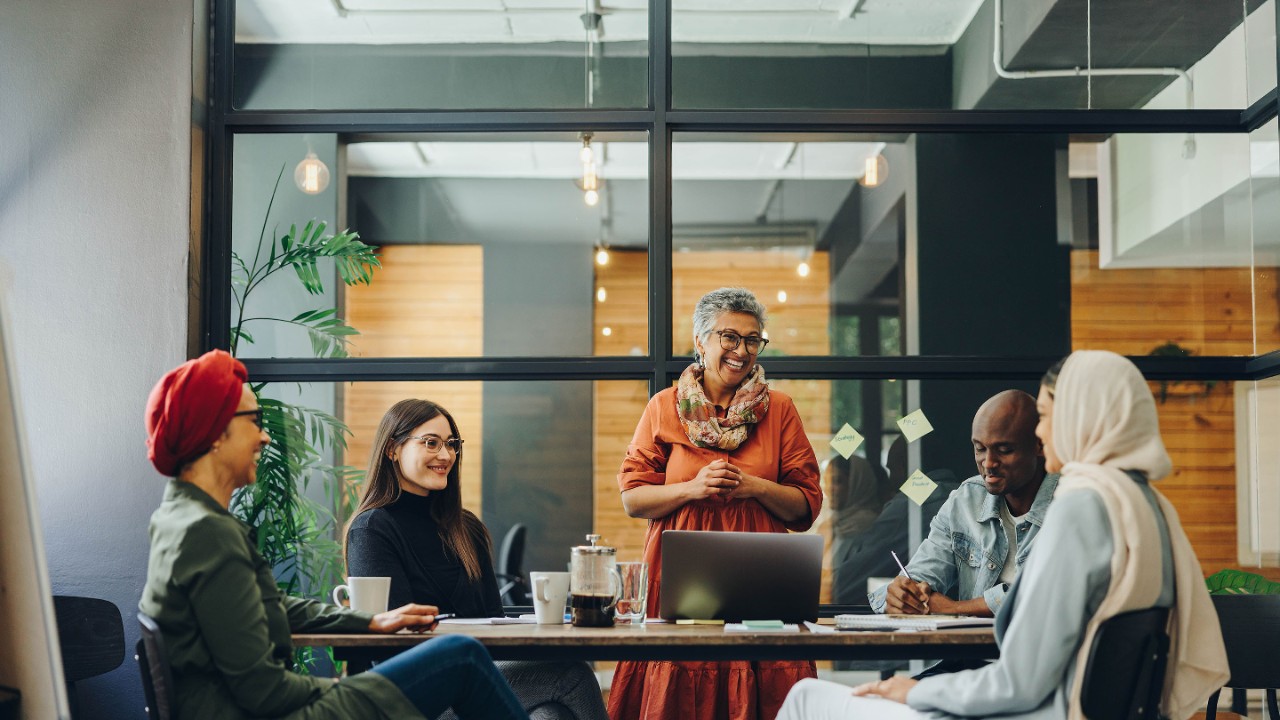 Successful businesspeople smiling happily during a meeting in a creative office. Group of cheerful business professionals working as a team in a multicultural workplace.