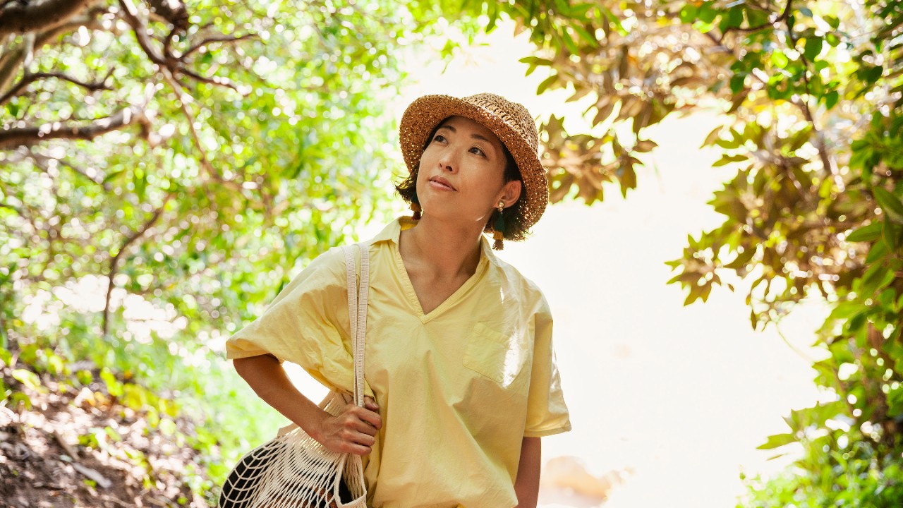 Mujer con camisa amarilla brillante caminando por un bosque