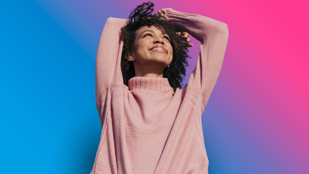 on blue to pink gradient background female pink sweater outdoors