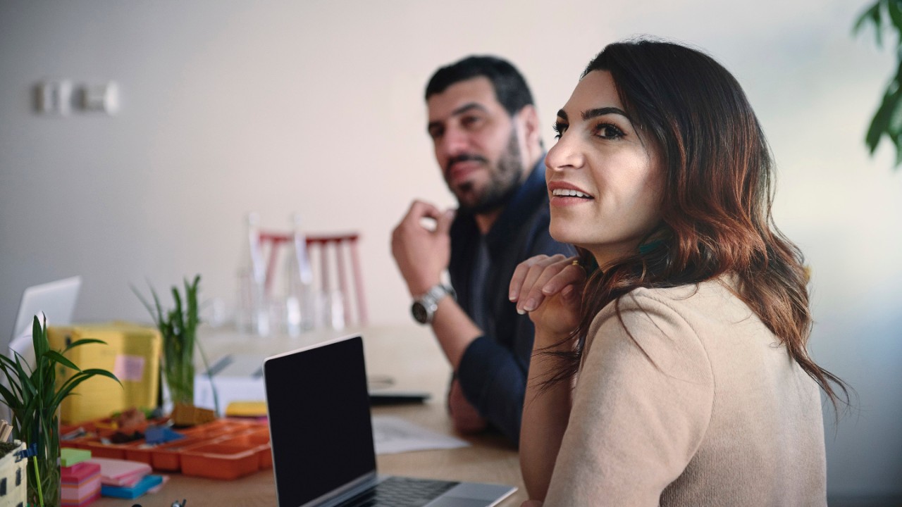 Female and male engineers looking away while sitting at table in office