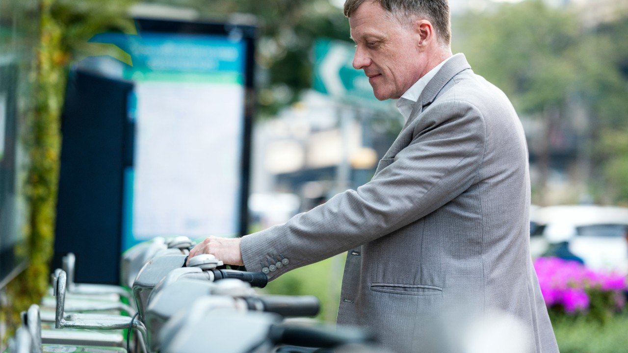 A Businessman choosing bicycle in a public bicycle service area. Bicycle-sharing system concepts.