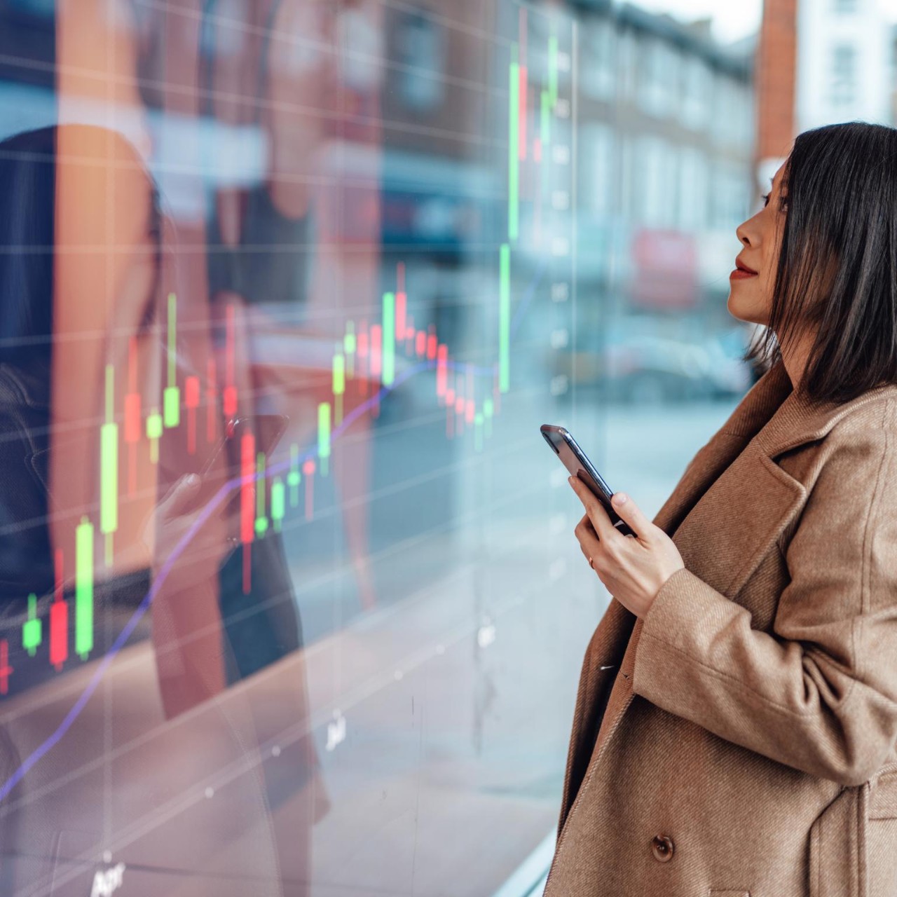 Young Asian businesswoman analysing and checking stock market over smartphone