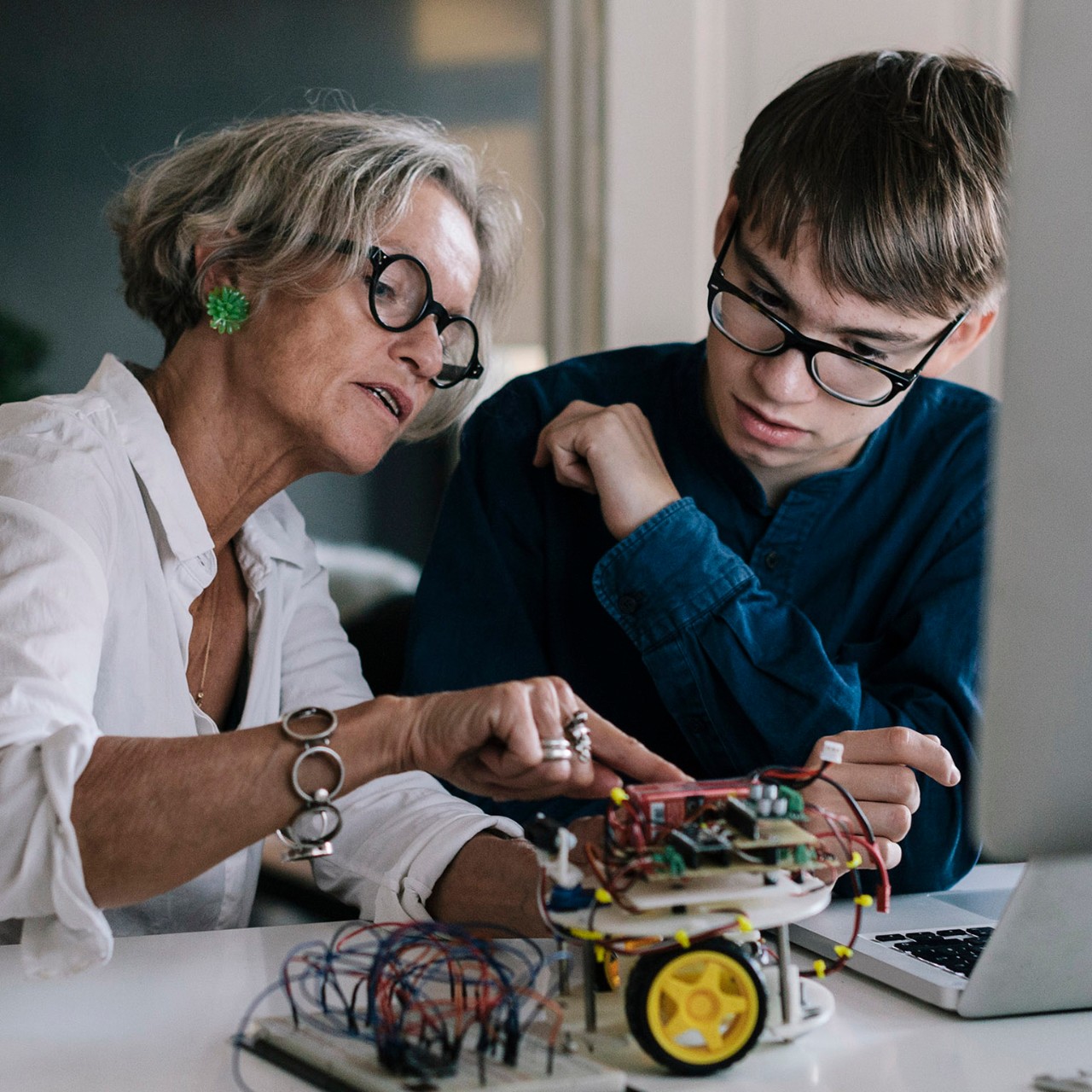 Mother  teaching her teenage son about hobby electronics.