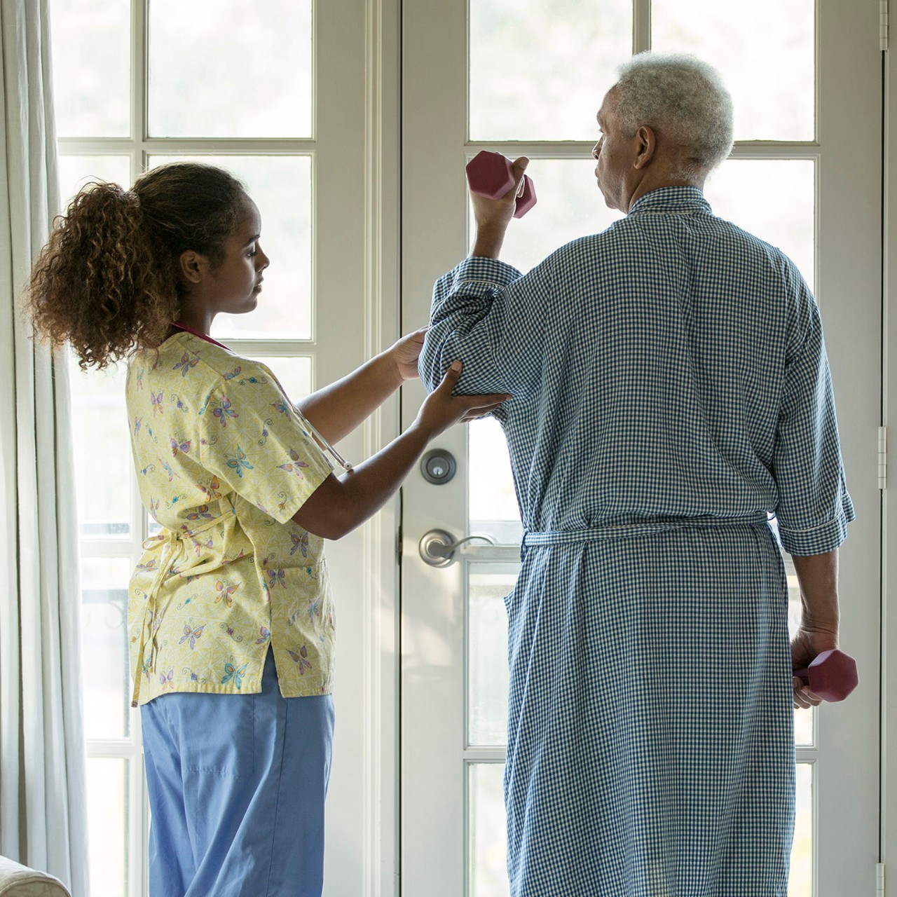 African American nurse helping patient with physical therapy