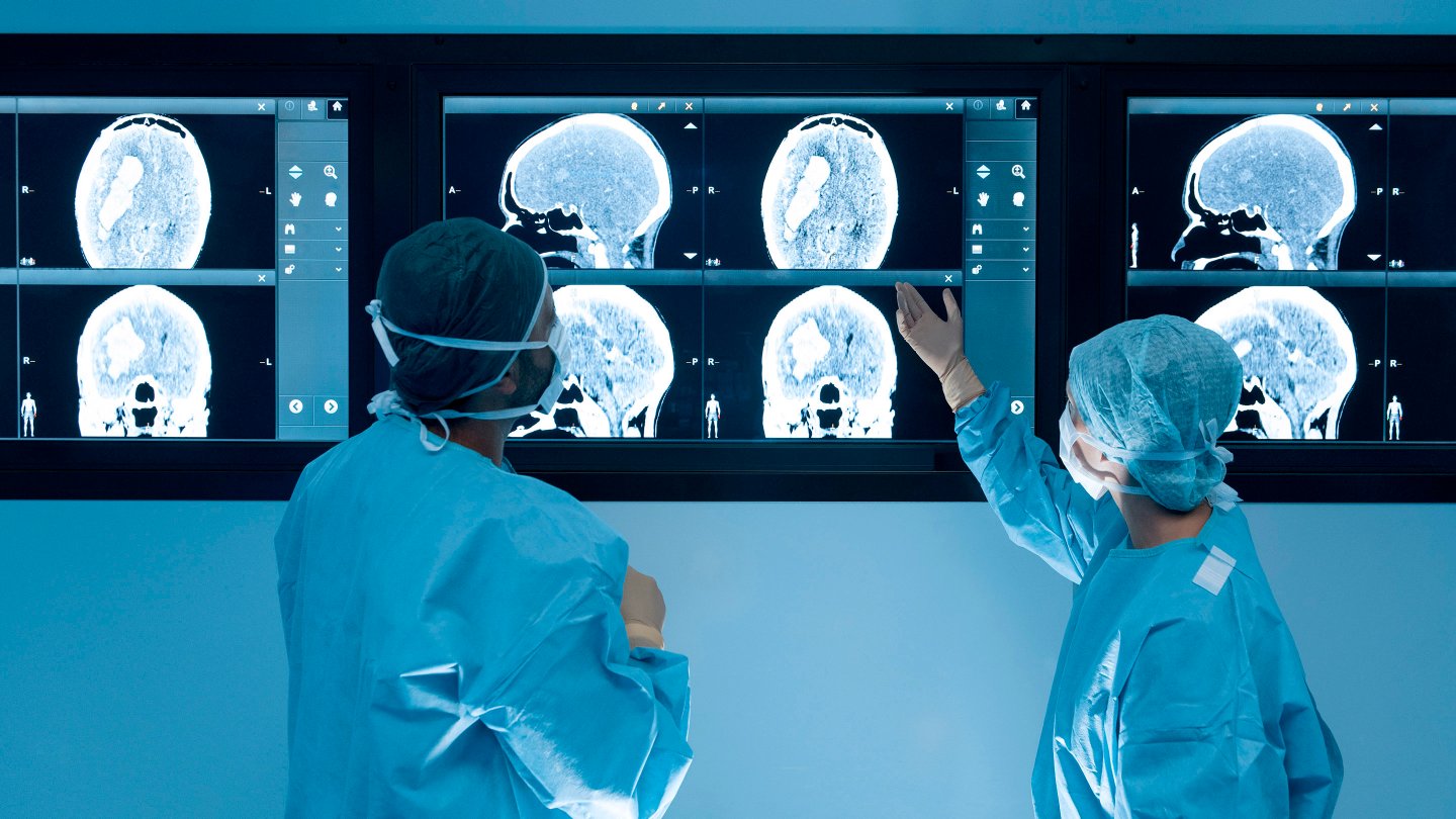  Surgeons looking at magnetic resonance imaging (MRI) brain scans during brain surgery.