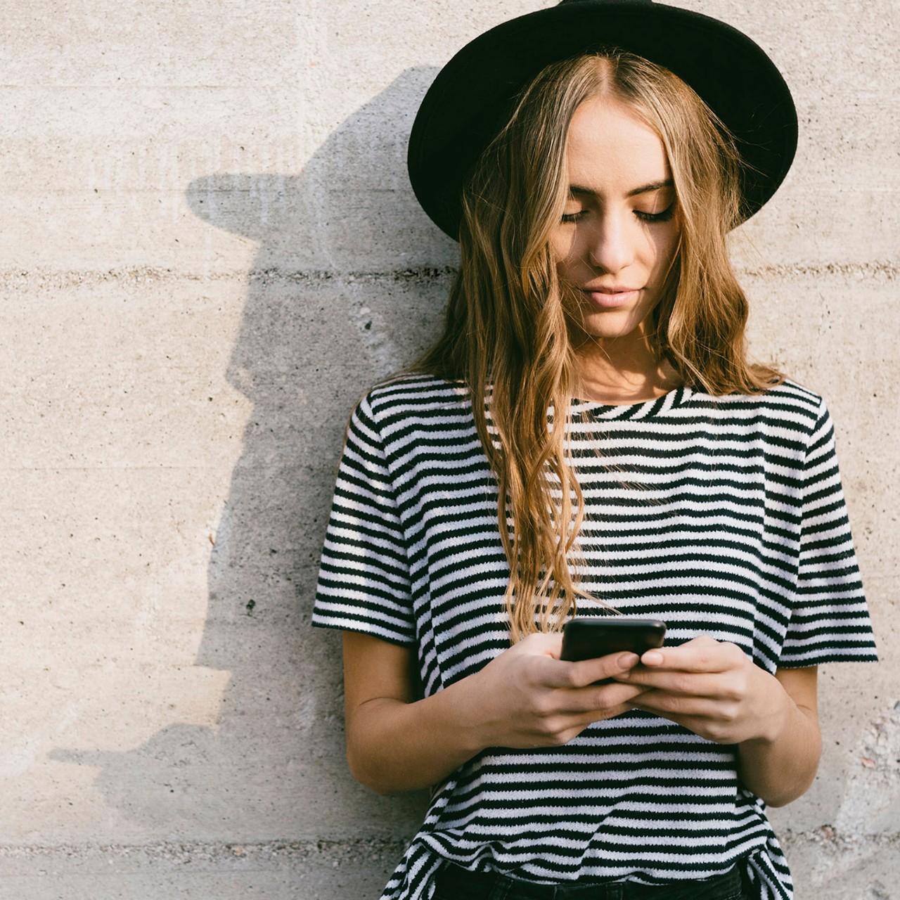woman with hat on smartphone
