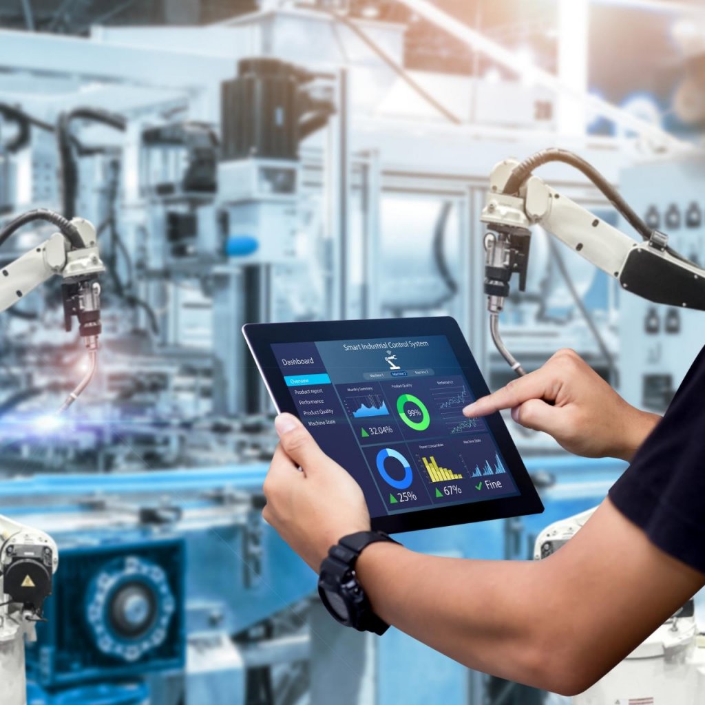 Hands holding tablet on blurred automation machine as background