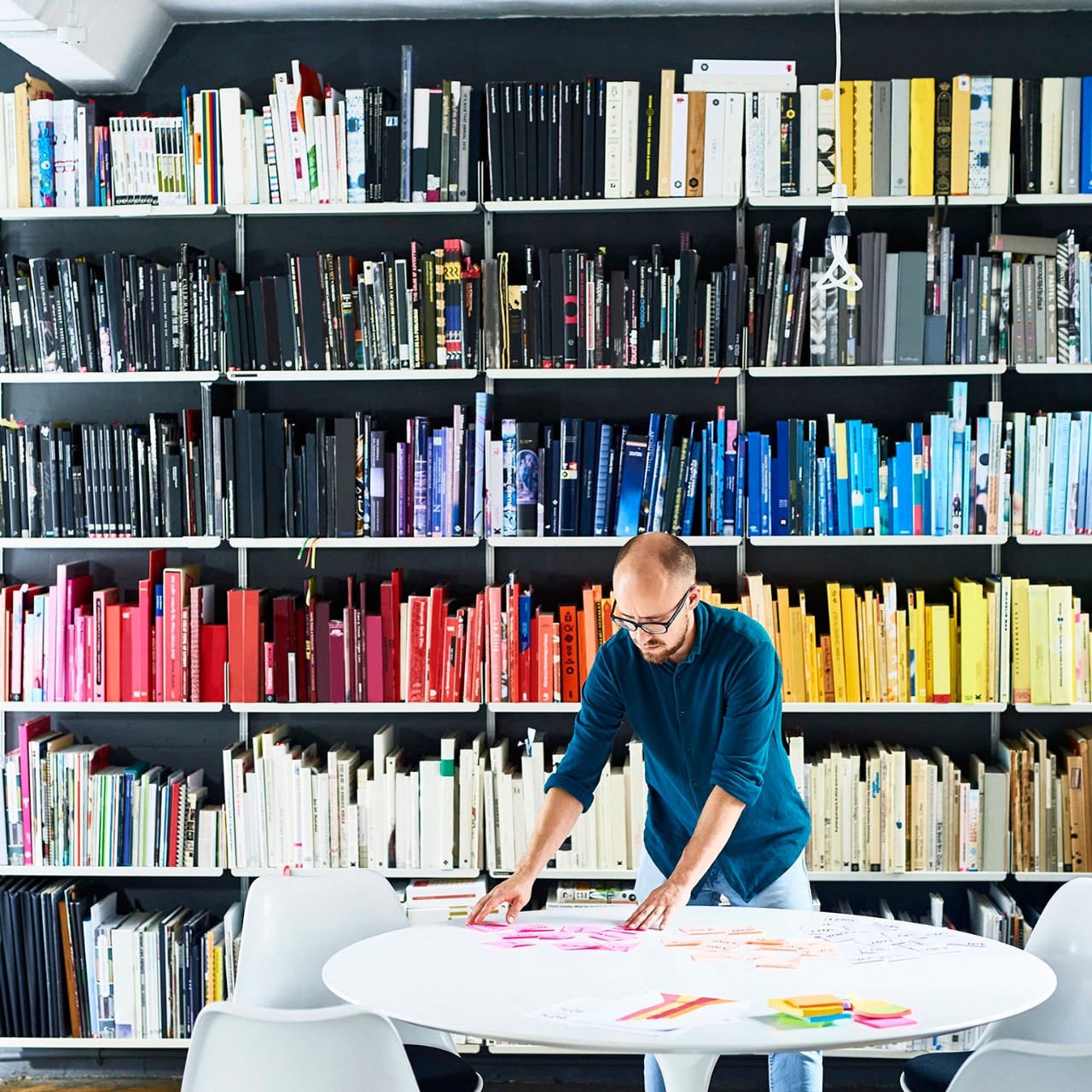 Man working in creative studio in front of colorful bookshelves