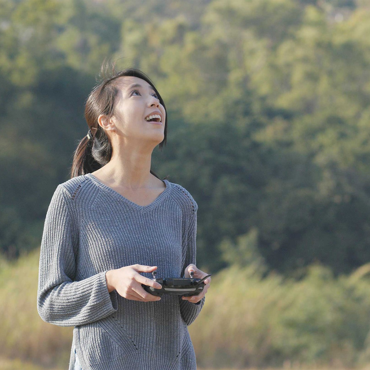 Woman controling flying drone in the park 