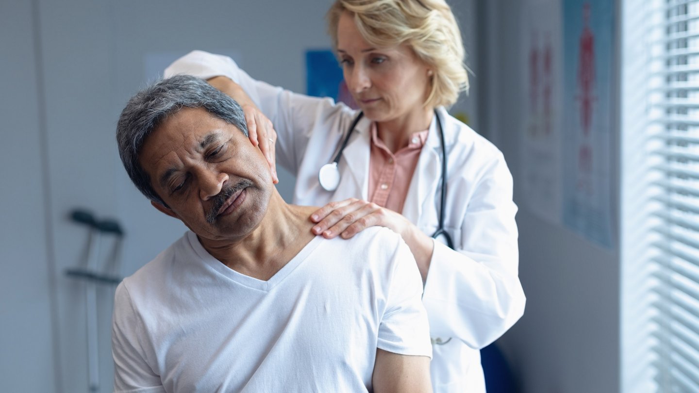827154 Front view of Caucasian female doctor examining mixed-race male patient neck in hospital