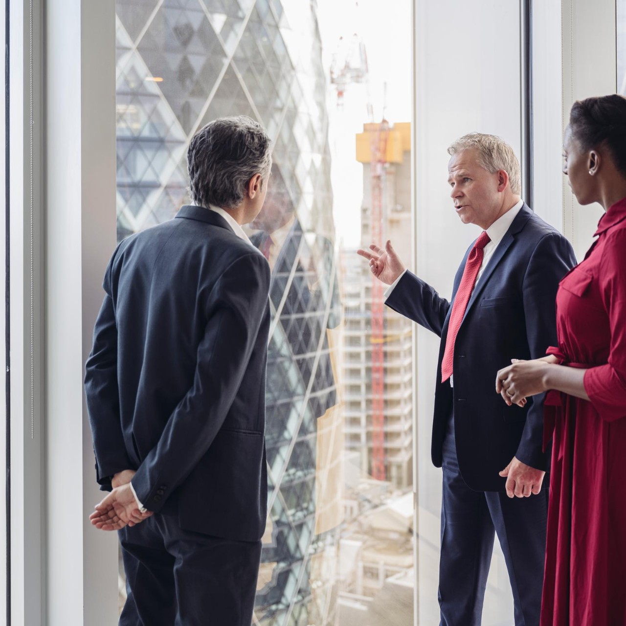 Male and female businesspeople standing at full length window of modern office building