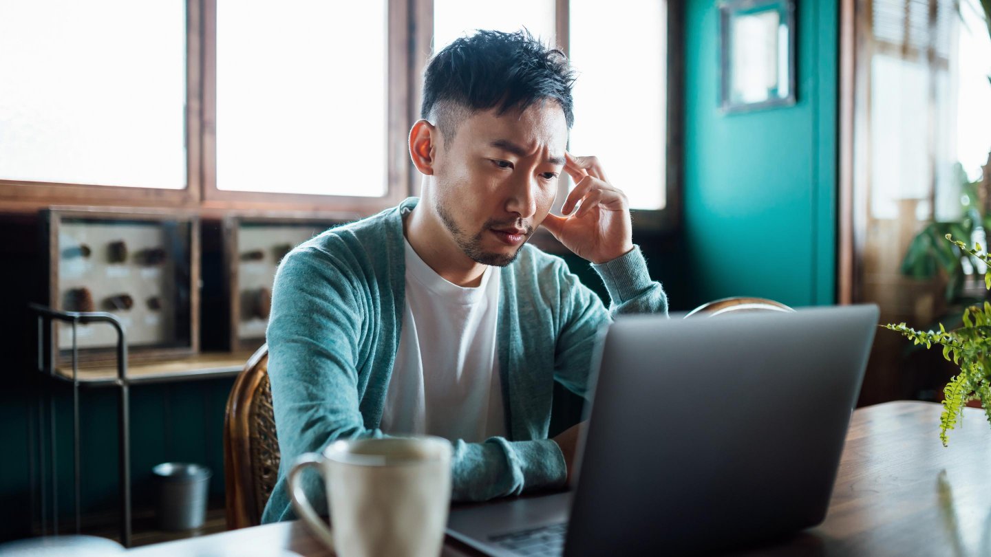 man in front of laptop looking worried