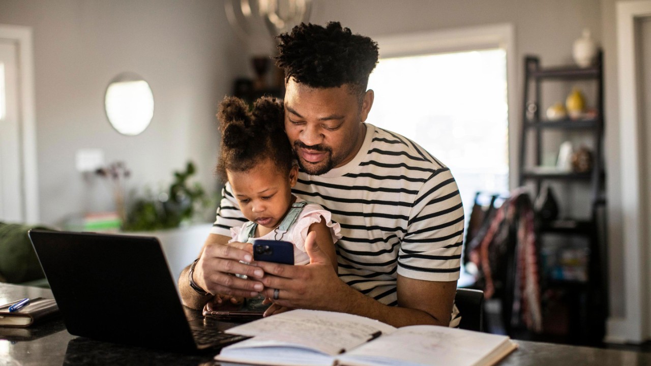 Father working from home while holding toddler