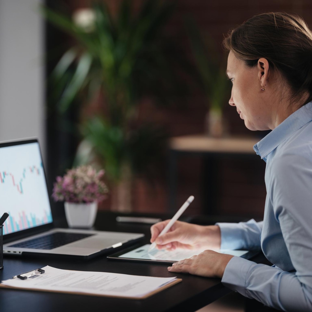 woman-on-laptop-and-cell-phone-with-data-printouts