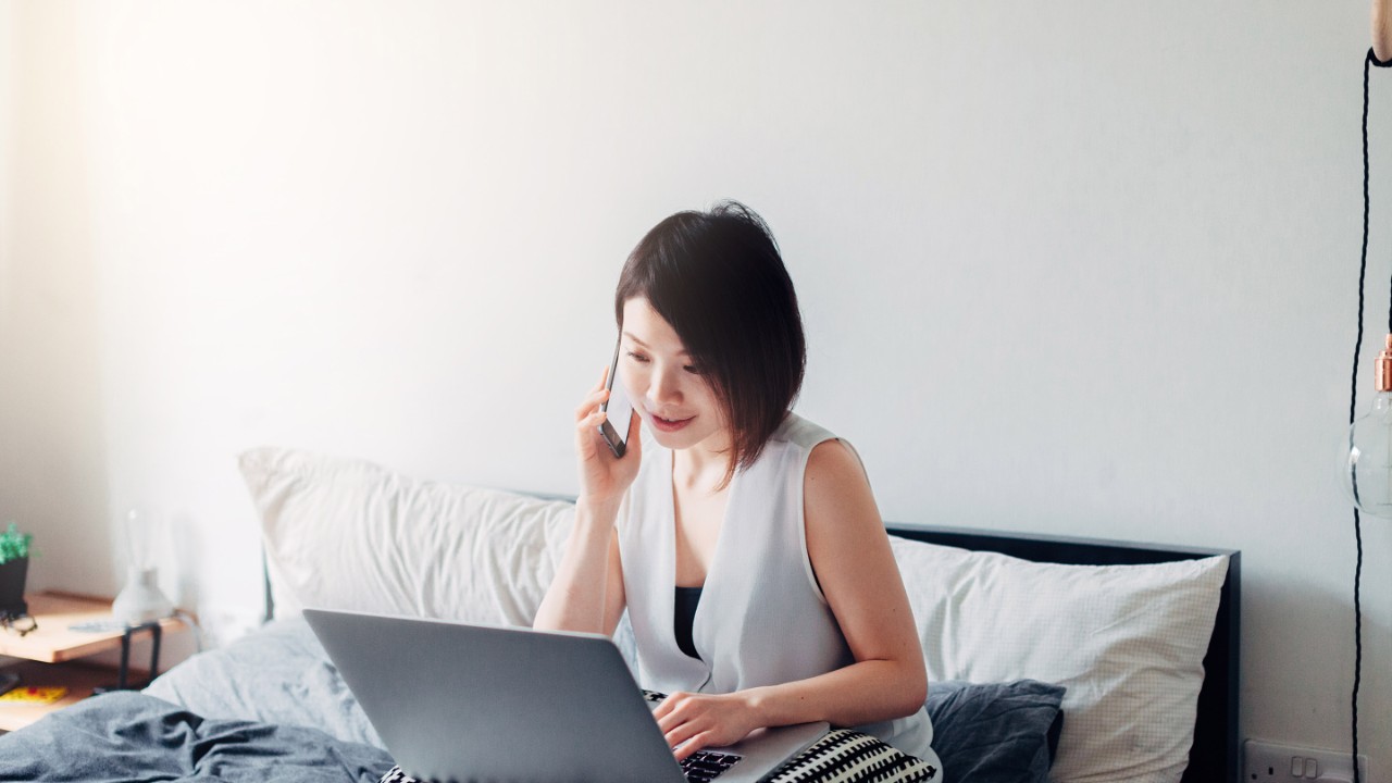 Young woman working from home on bed