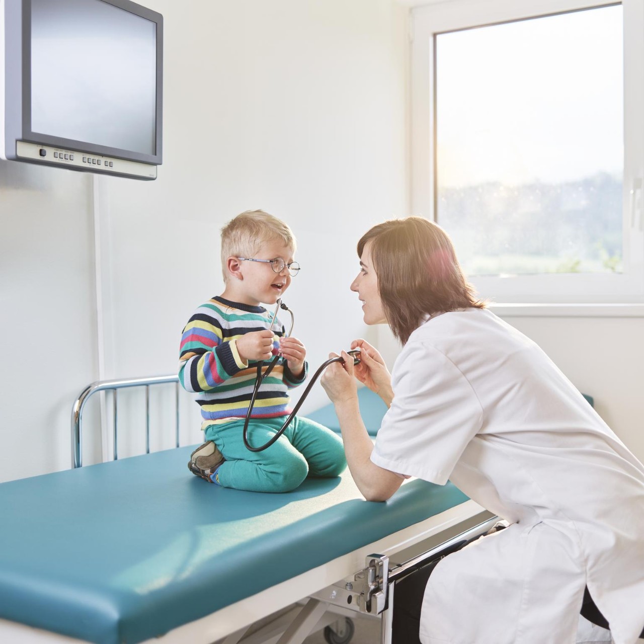 Female doctor and boy with stethoscope in medical practice, healthcare