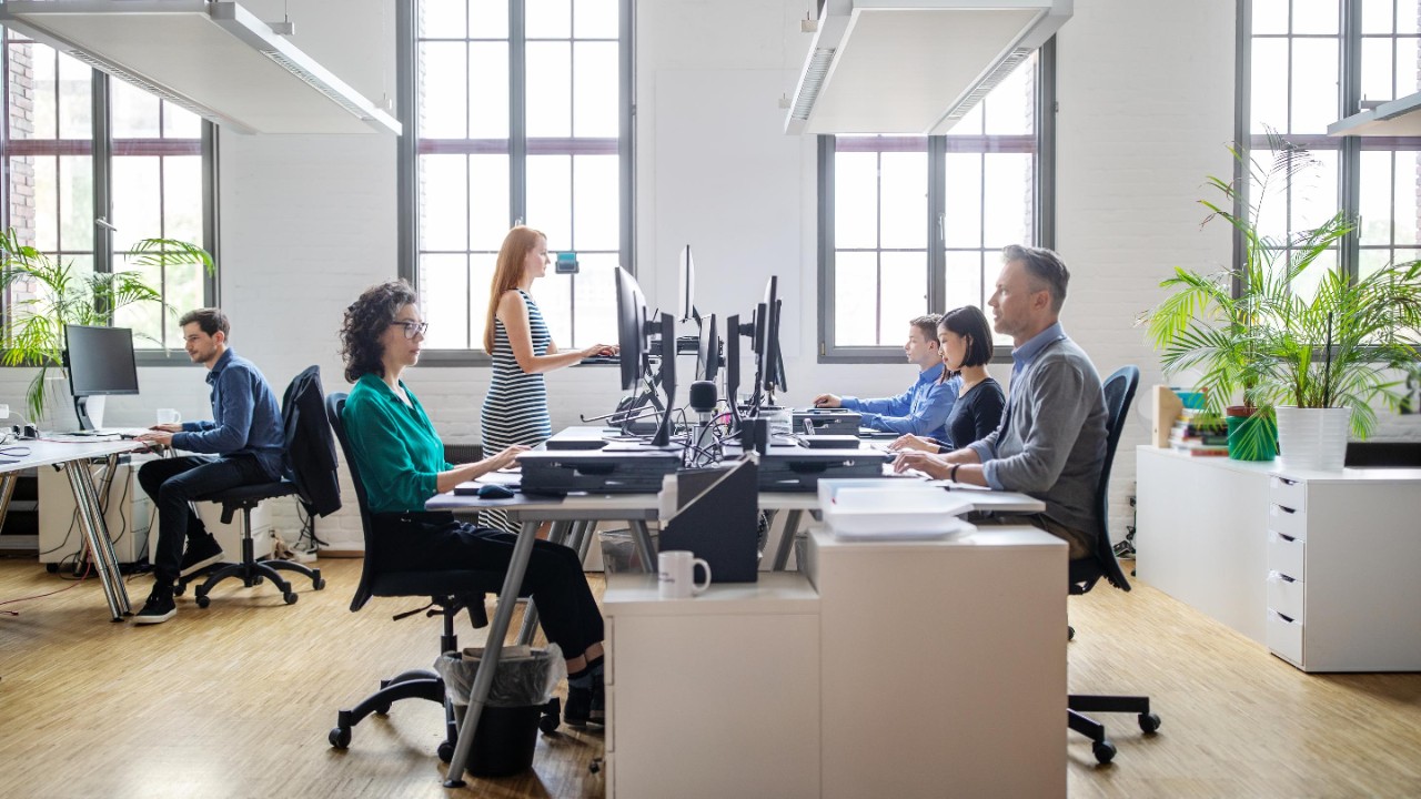 Business people at their desks in a busy, open plan office