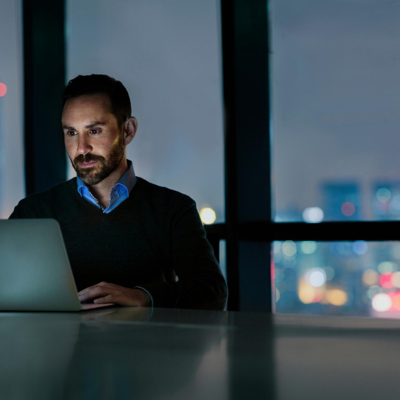 Man viewing laptop computer in office at night