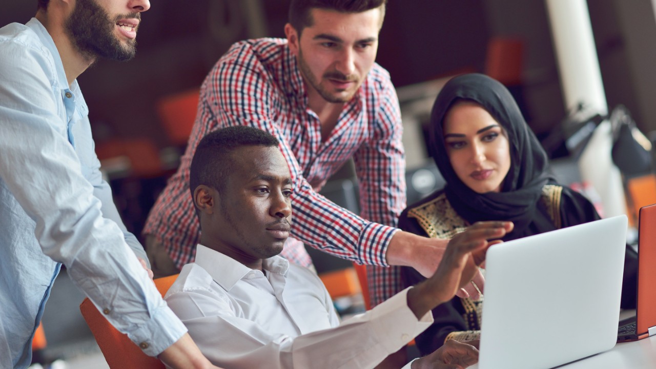 Multiracial contemporary business people working connected with technological devices like tablet and laptop, talking together - finance, business, technology concept