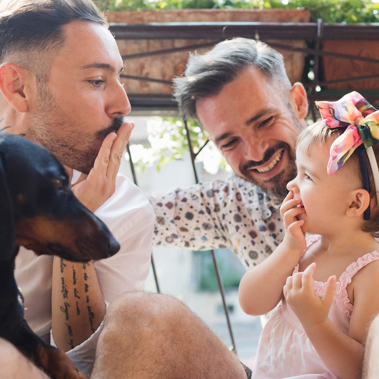 happy gay couple with dog and daughter on balcony