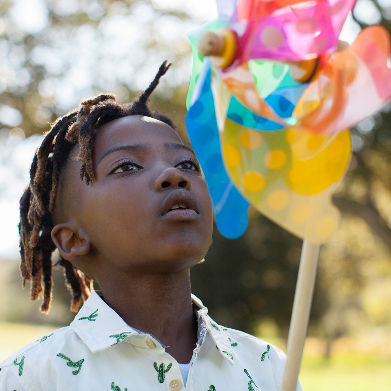 Young African boy blowing windmill in nature