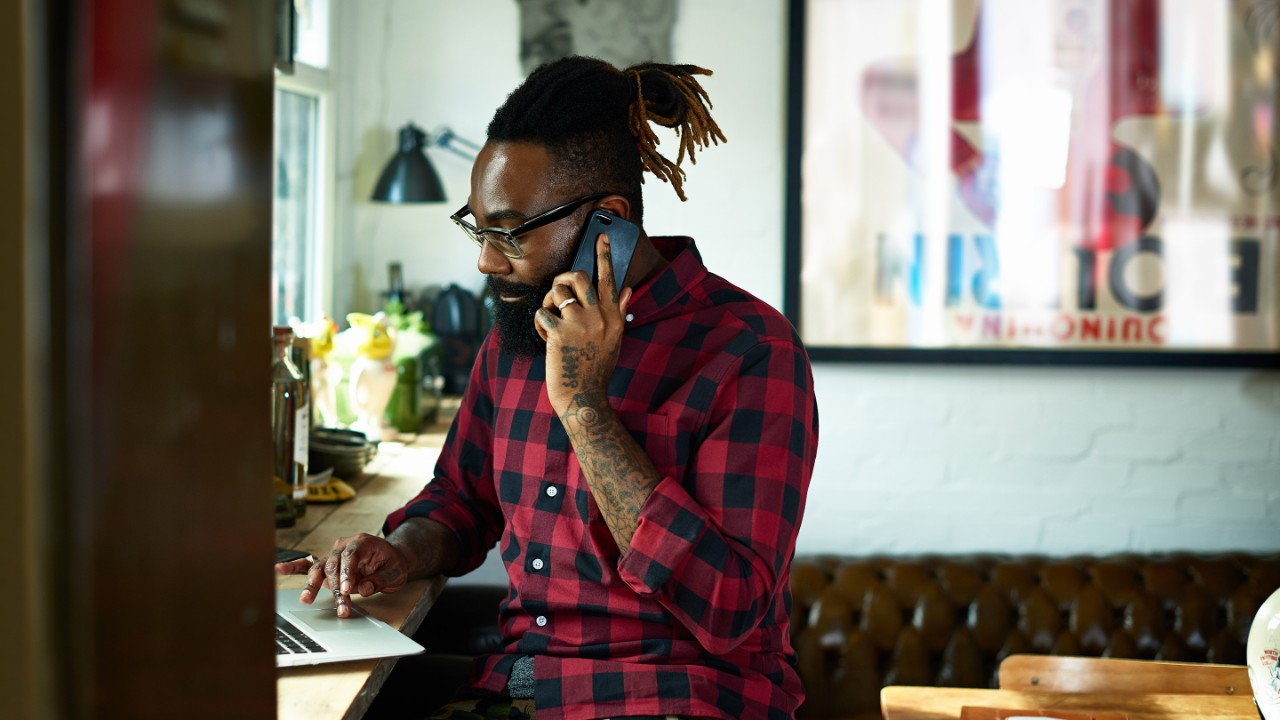 Uomo che lavora al suo computer portatile in un’area pranzo
