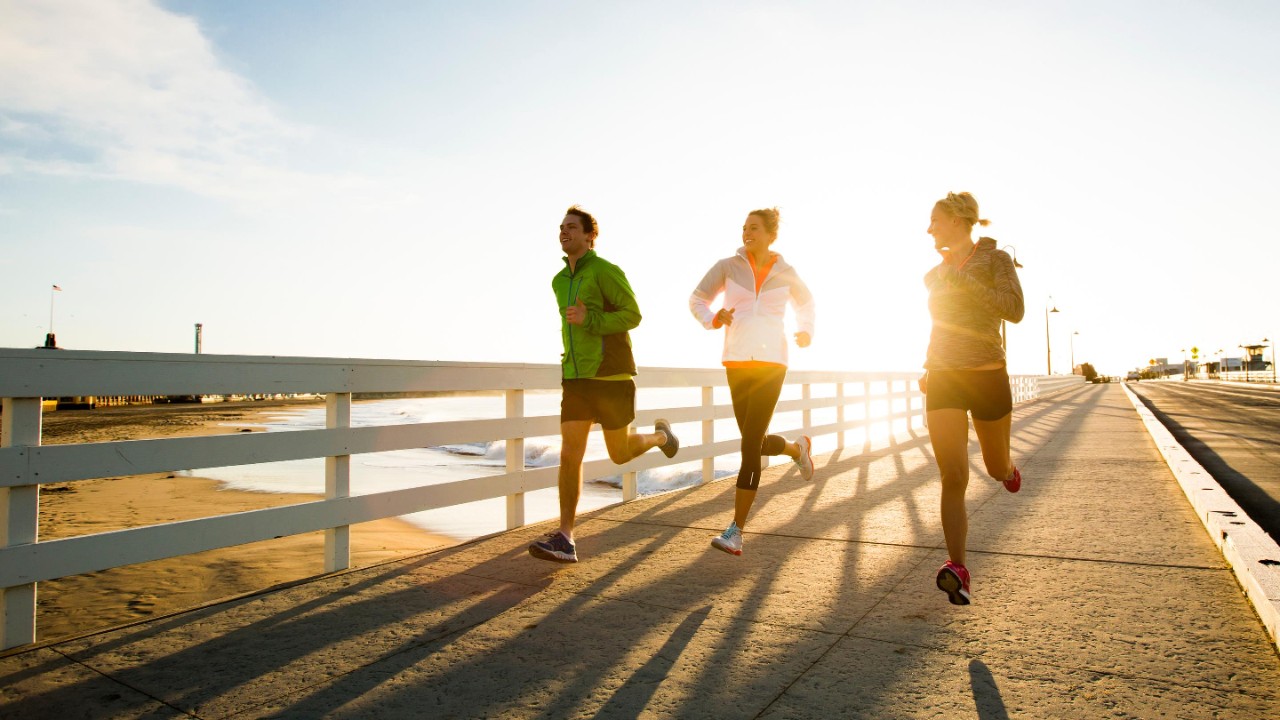 Friends running a boardwalk near the Pacific Ocean