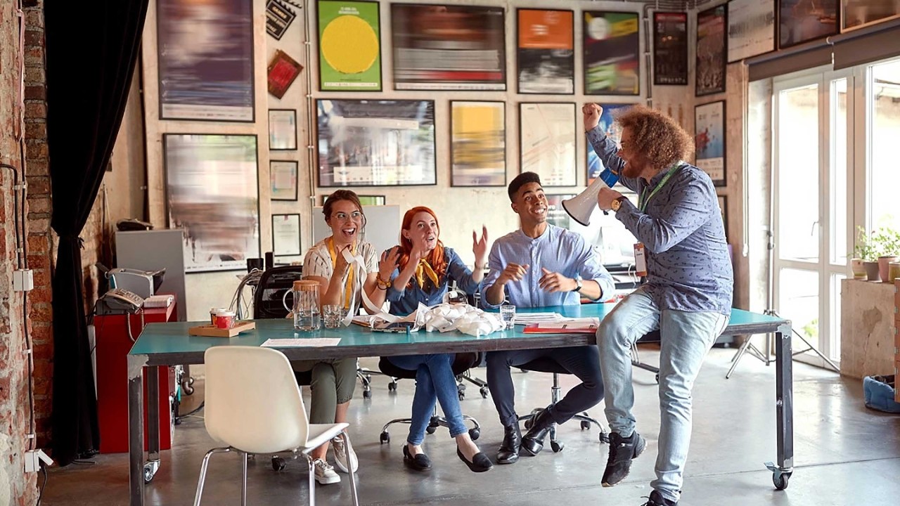 Un gruppo di giovani dipendenti allegri si diverte a lavorare insieme in ufficio