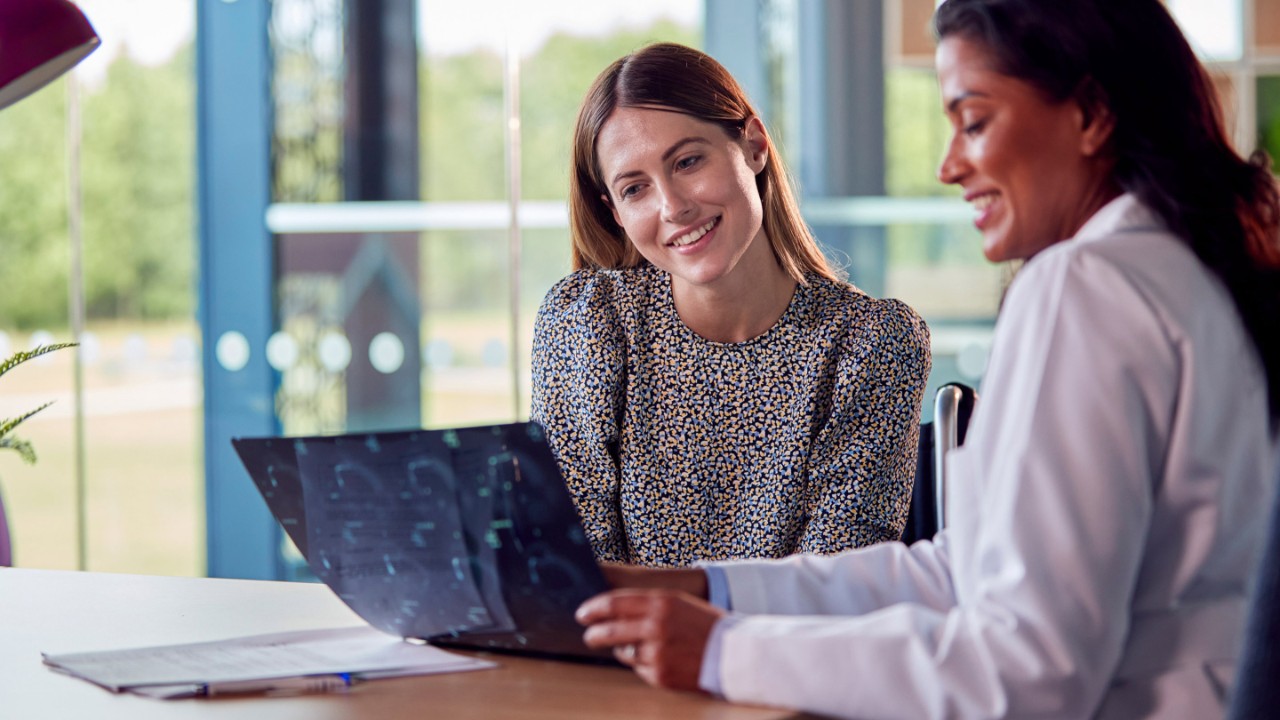 入院中の笑顔の女性患者とスキャン結果について話し合う女性医師