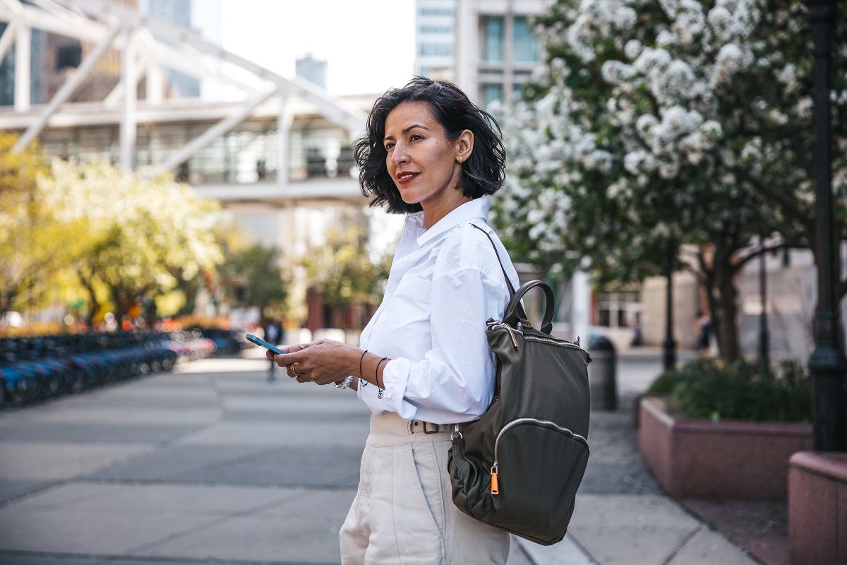 Businesswoman busy on mobile phone out of the office while waiting for the bus in New York Financial district downtown.