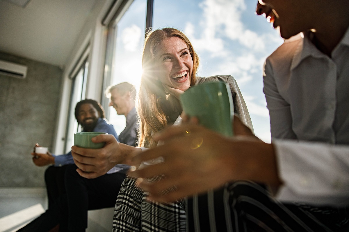 Group of entrepreneurs on a break in the office. Focus is on happy redhead businesswoman talking to her colleague.