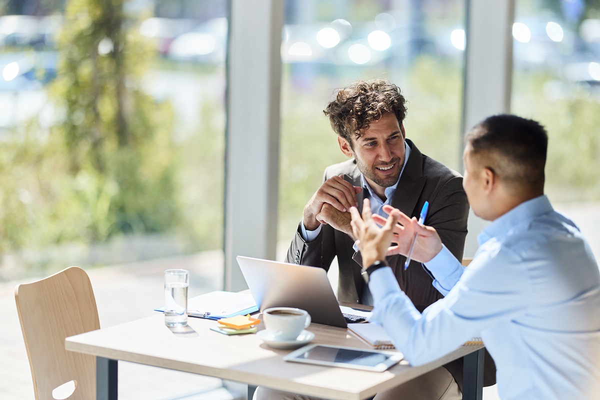 Happy businessman talking to his colleague while working on a meeting in the office.