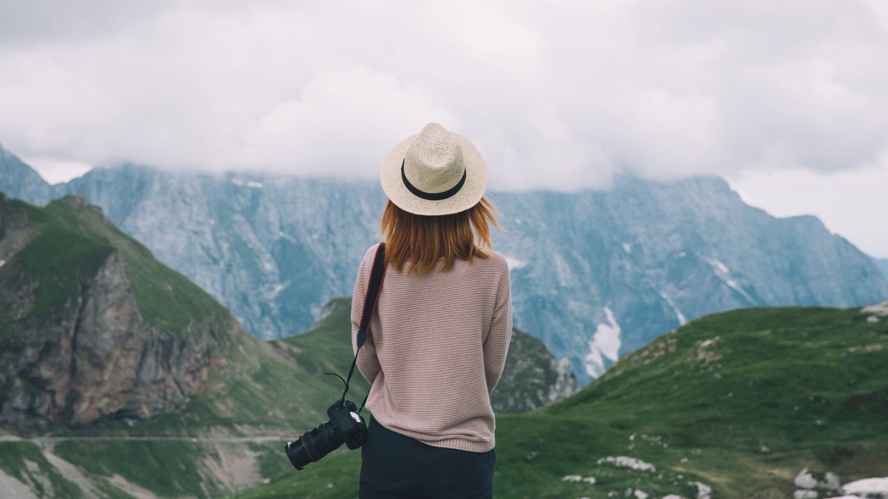 Young woman relaxing outdoor travel freedom lifestyle with mountains on background. Fashionable girl in the Mangart is a mountain in the Julian Alps, located between Italy and Slovenia.