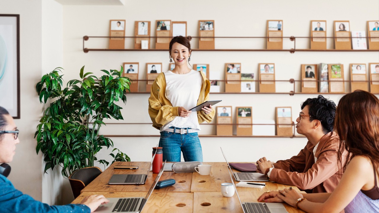 Grupo de jovens profissionais japoneses trabalhando em laptops em um espaço de trabalho conjunto.