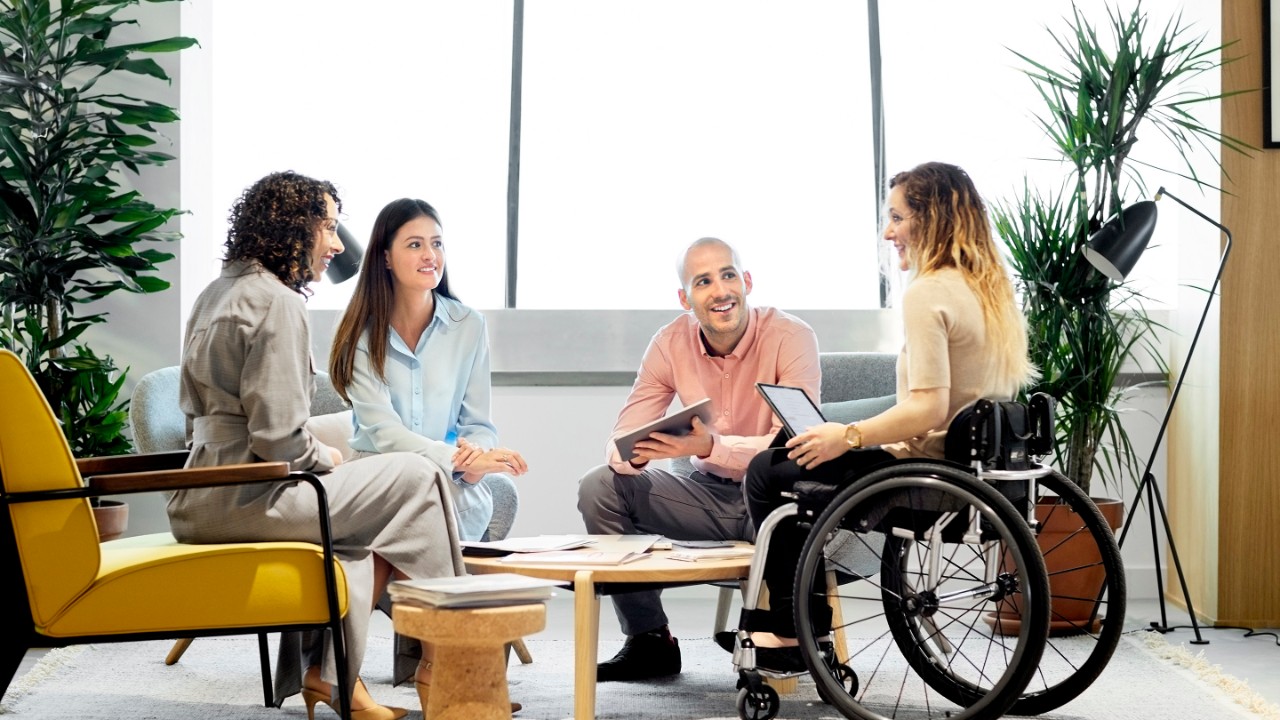 Disabled businesswoman discussing with colleagues. Male and female professionals planning in business meeting. They are sitting at office.