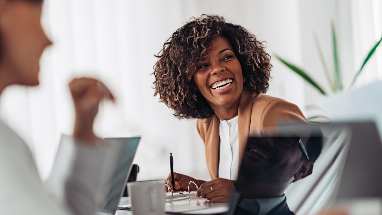 Portrait of cheerful african american businesswoman discussing and smiling at the meeting with colleagues